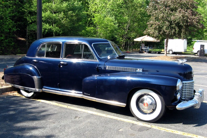 a classic car sitting in the middle of a parking lot