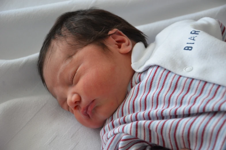 a close up of a baby sleeping wearing a blanket