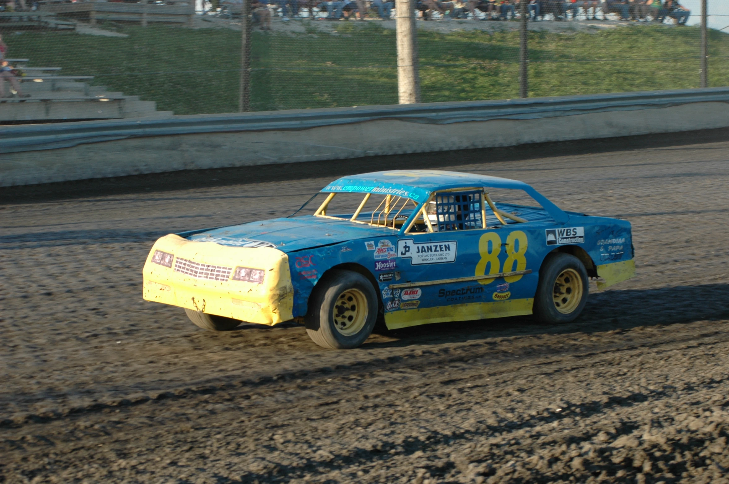 a man driving a vintage car on top of a dirt track