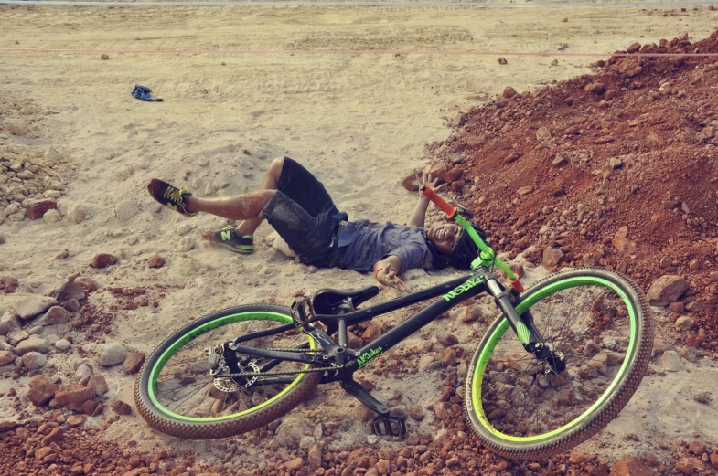 a man with a bicycle is lying on the ground