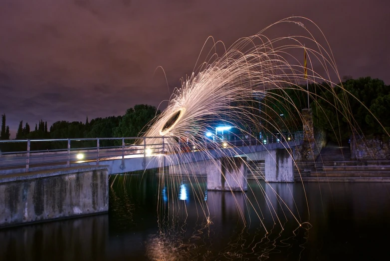 a stream of light streaks across the air over water