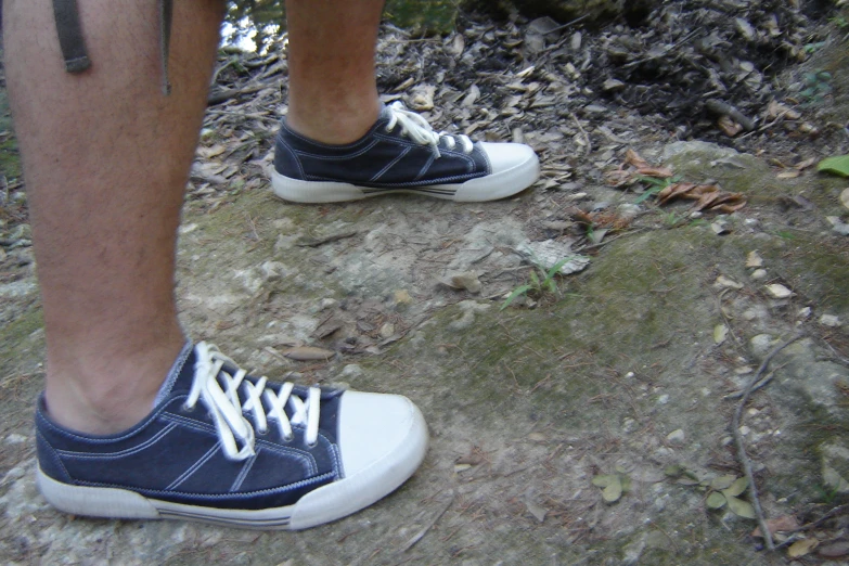 a close up of a persons feet standing on top of a dirt ground