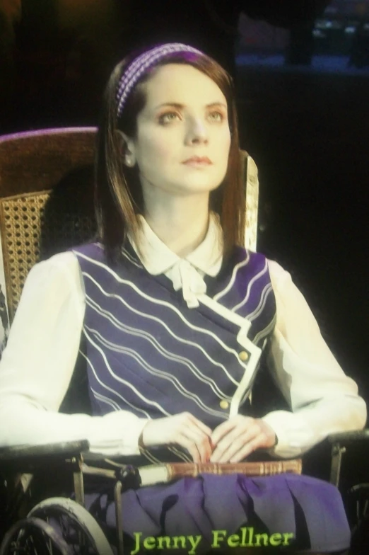 a woman sitting in a chair wearing a purple and black dress