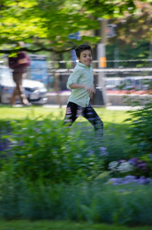 a boy running through the grass with purple flowers