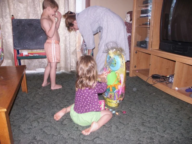 two children and a woman looking at a television