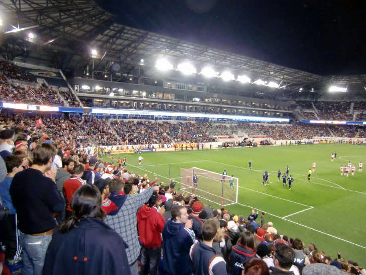 a crowd of people watching two teams play soccer in a stadium