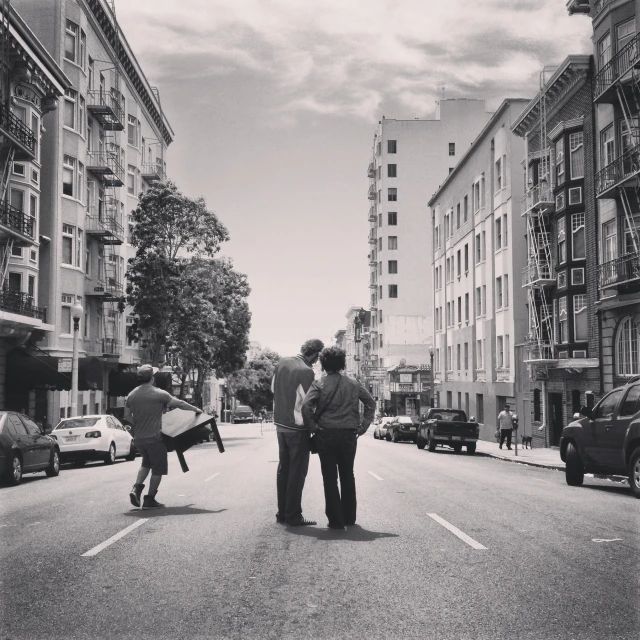 two guys talk while they are skateboarding down the street