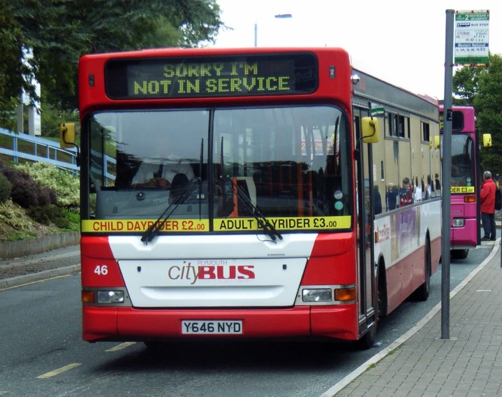 a red bus driving down a street near a sidewalk