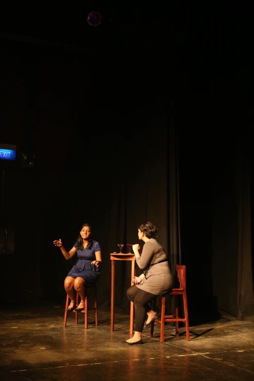 two women siting on chairs in a darkened room