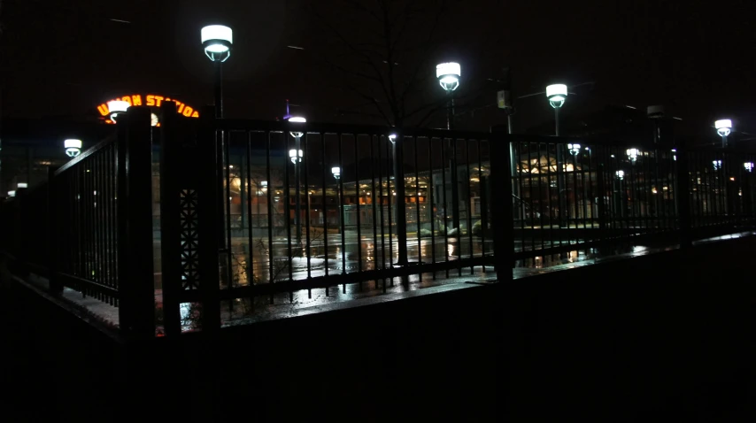 a dark street lit by some street lights and bright buildings