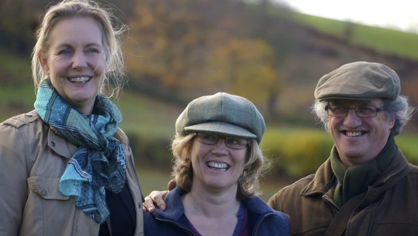 three people smiling while standing near each other