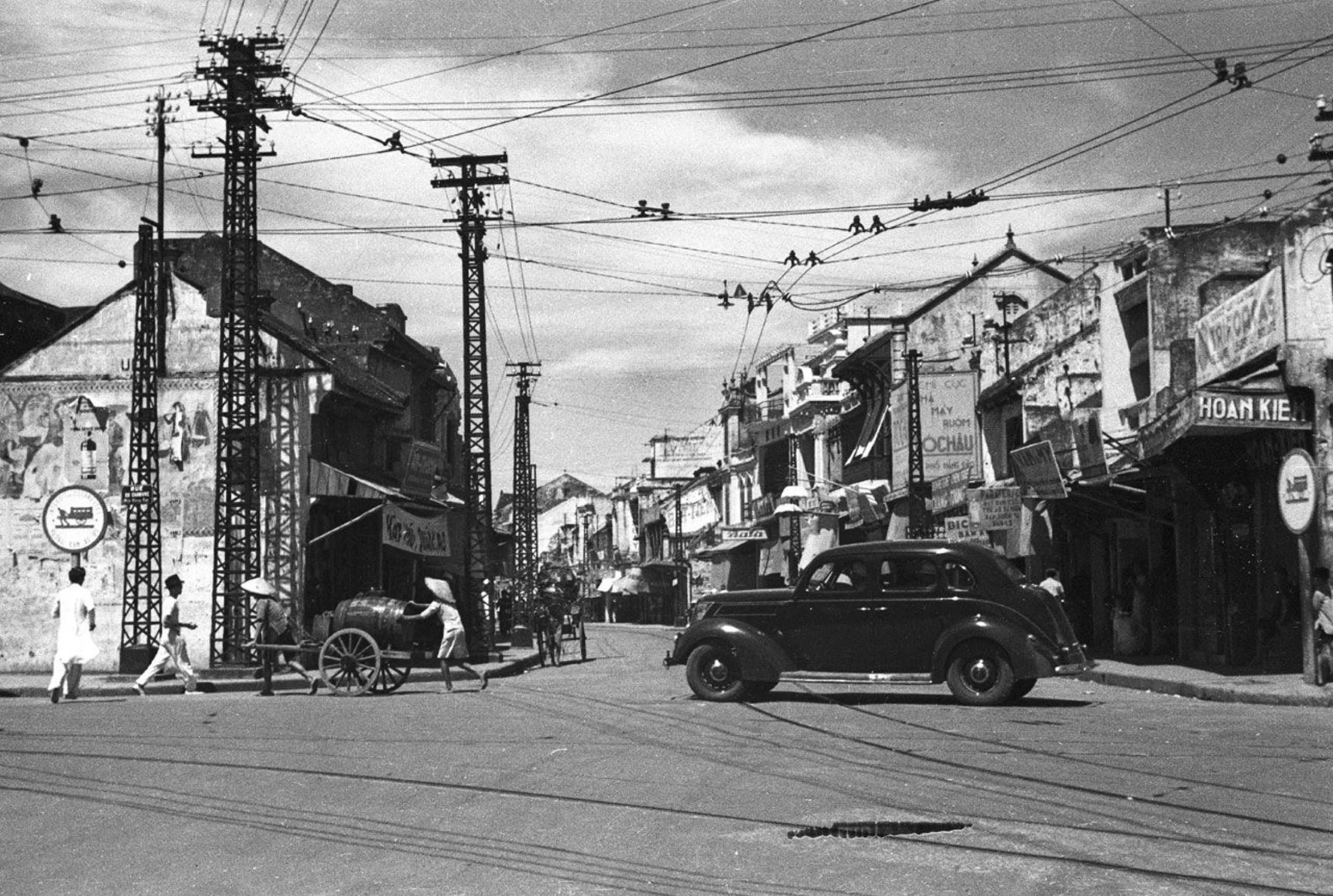 an old po of people in front of buildings and cars