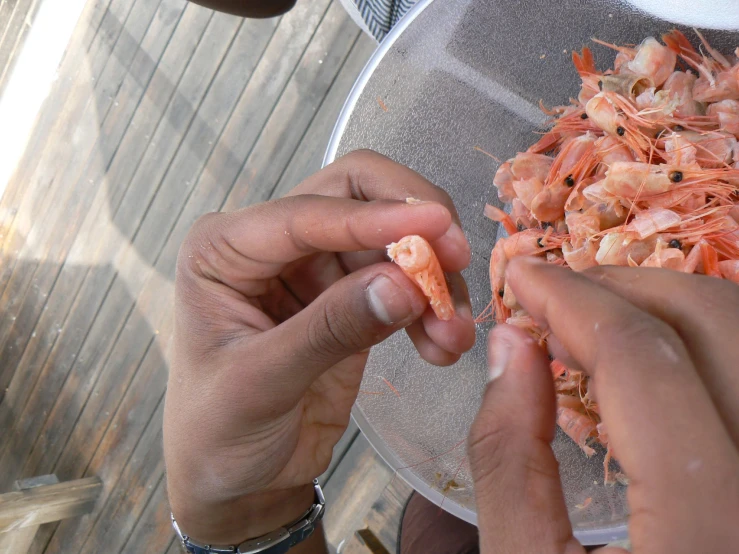 people hold shrimp in their hands and eat on the other