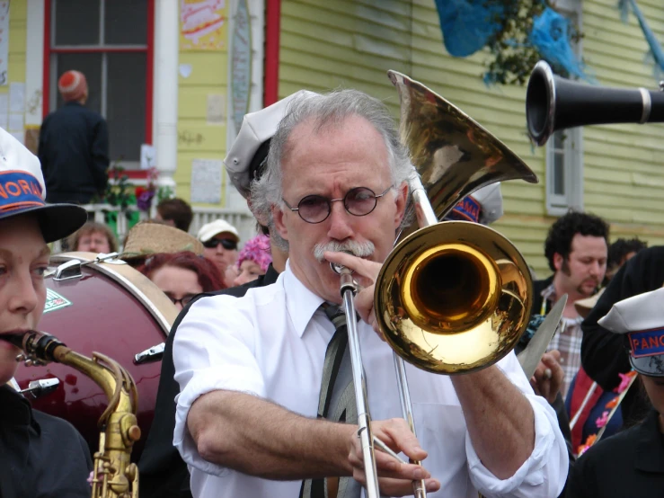a man plays a trumpet while standing next to other people