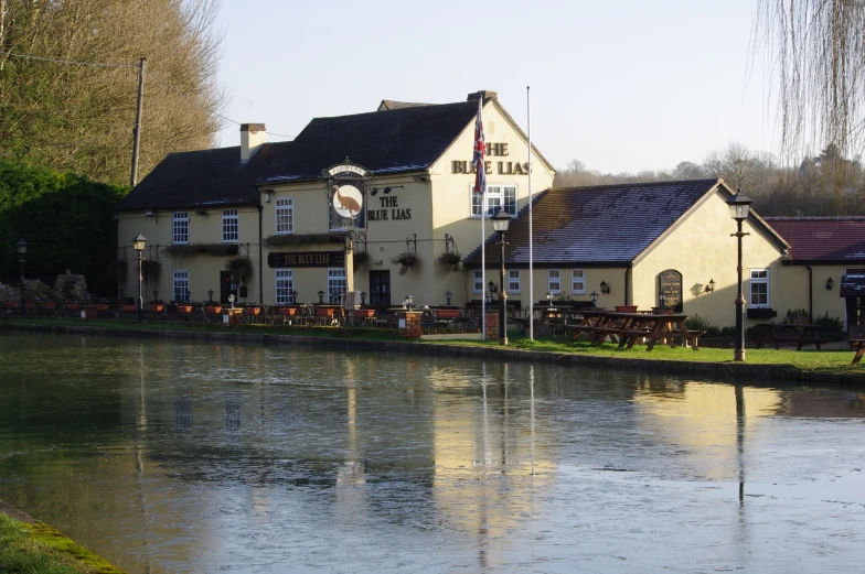 a river runs past a yellow building with blue roofs