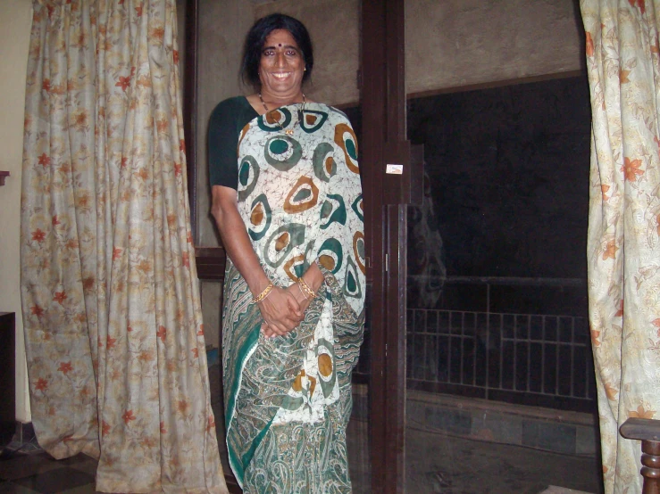 a woman with a green and white sari in front of a window