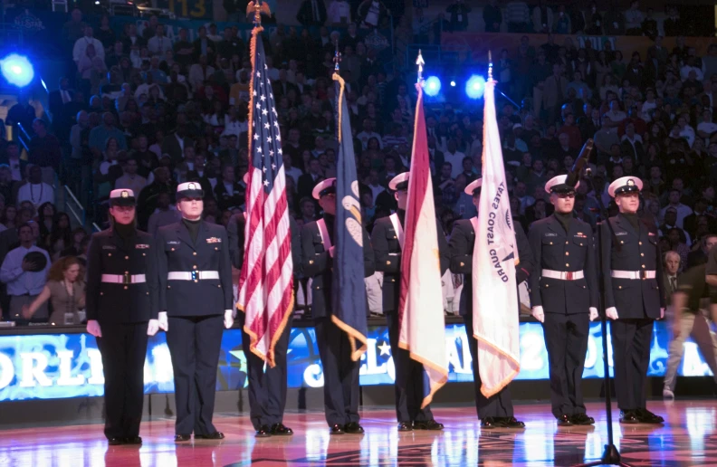 uniformed officers stand in formation next to american flags