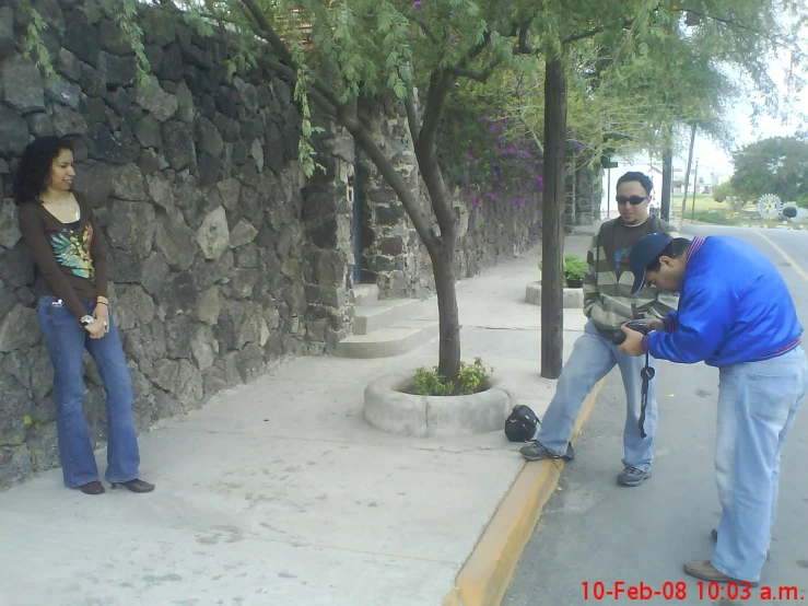 three people standing near the corner on the street