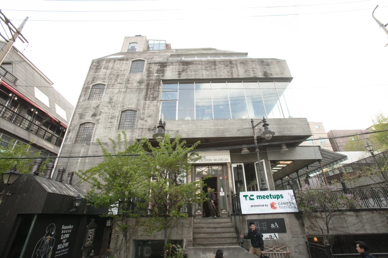 a building on the corner with a bunch of green trees in front of it