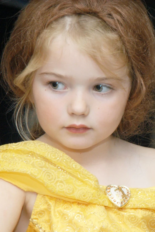 a little girl with blue eyes and wearing yellow