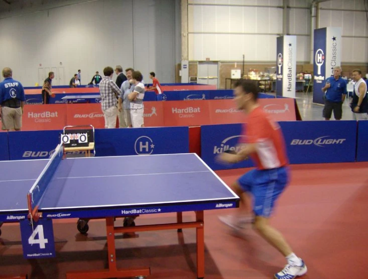 some people in an indoor room playing a game of ping pong