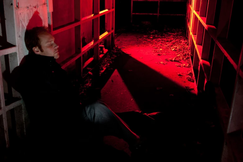 a man sitting down next to a barn in the dark
