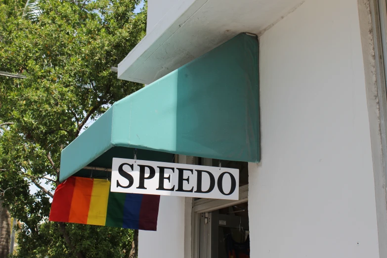 a rainbow - striped street sign is hung on a store front