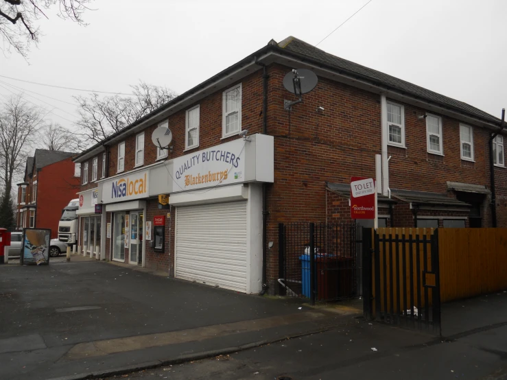 a brick and glass shop next to a wooden fence