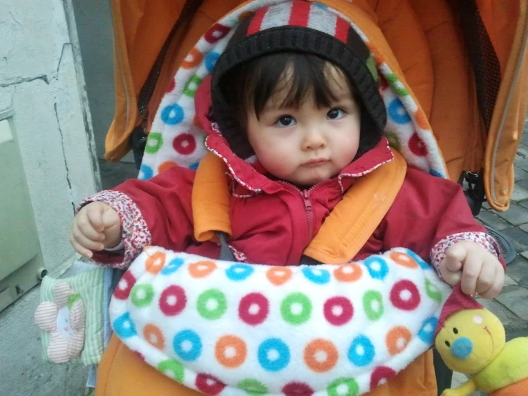 a little girl is standing in a stroller