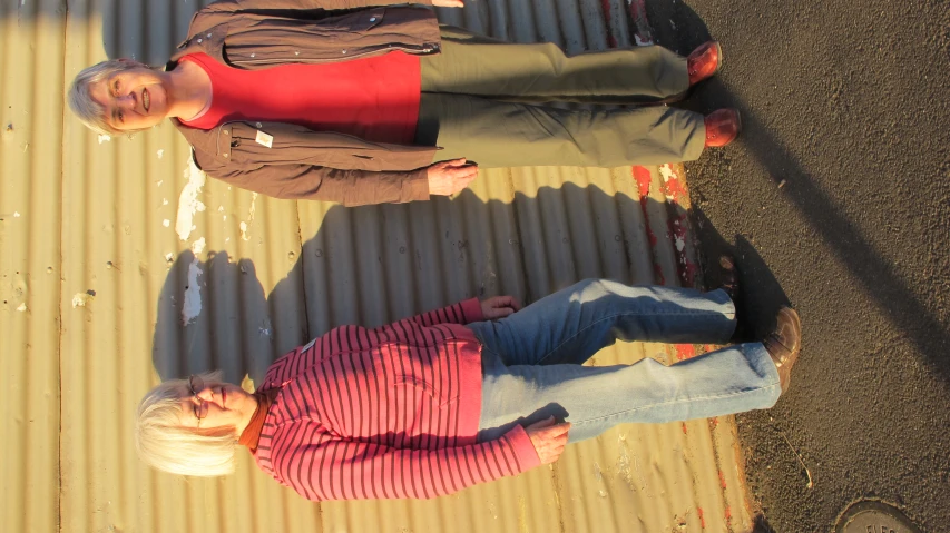 two women standing next to a corrugated building