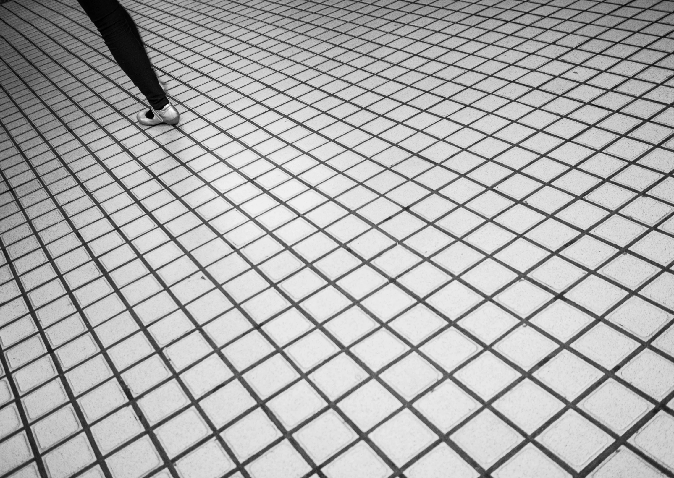 person walking across a tiled floor in the dark