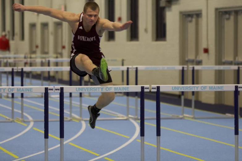 a young man is jumping over a hurdle