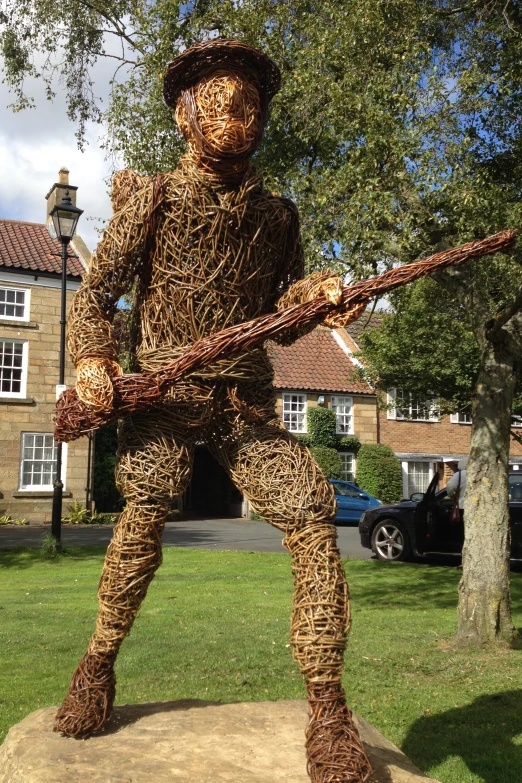 a man in straw woven sculpture with a rifle in his hand