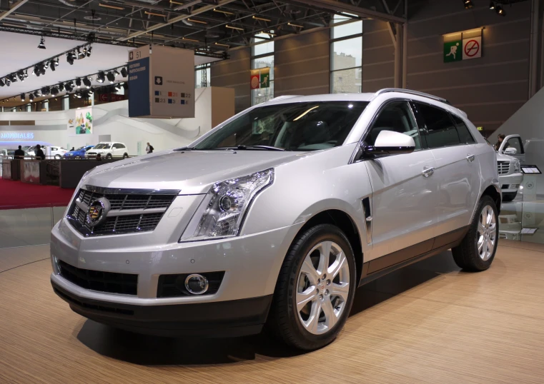 a silver cadillac srx at a showroom in a building