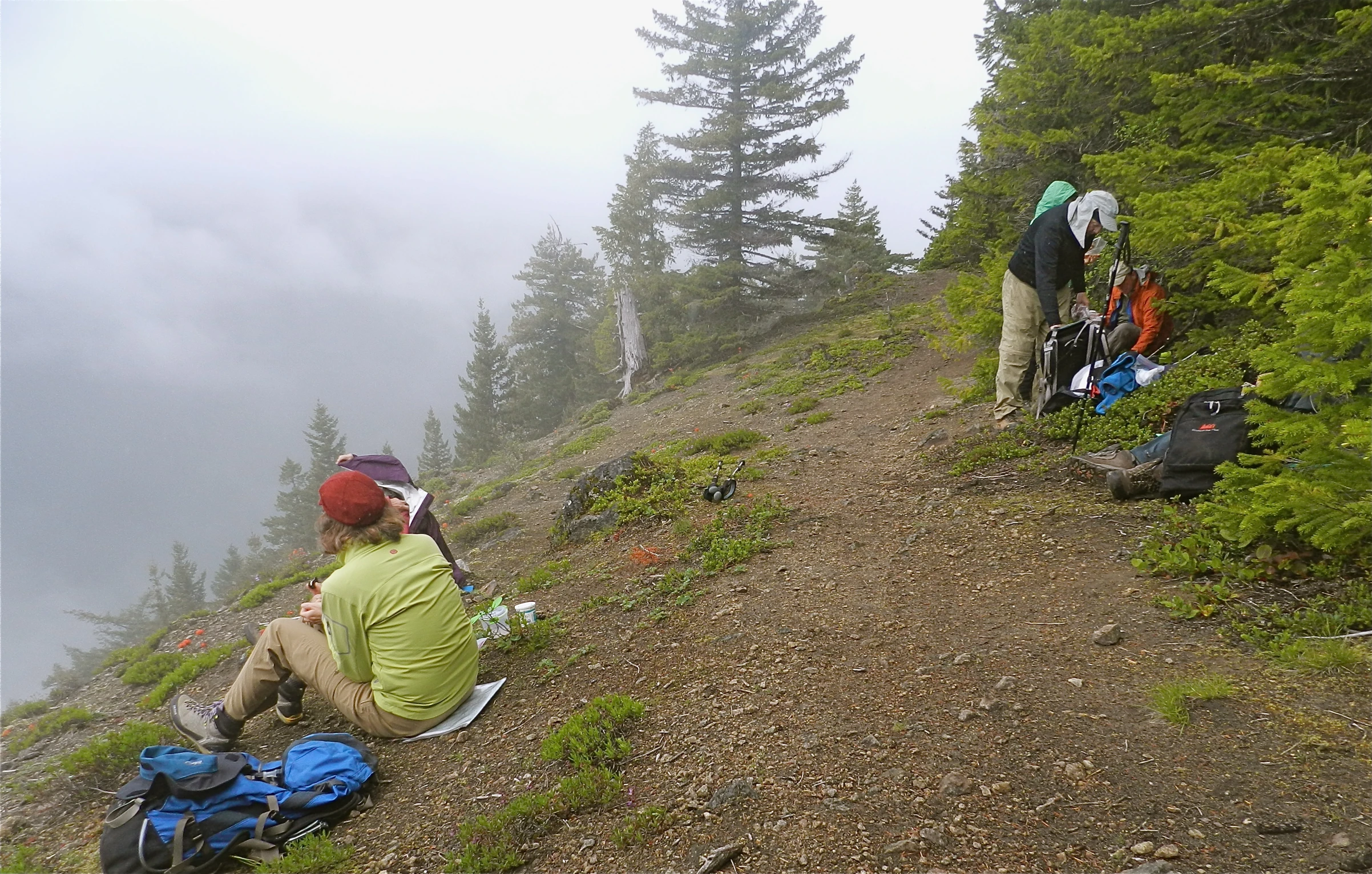 two people sitting on a mountain next to bikes