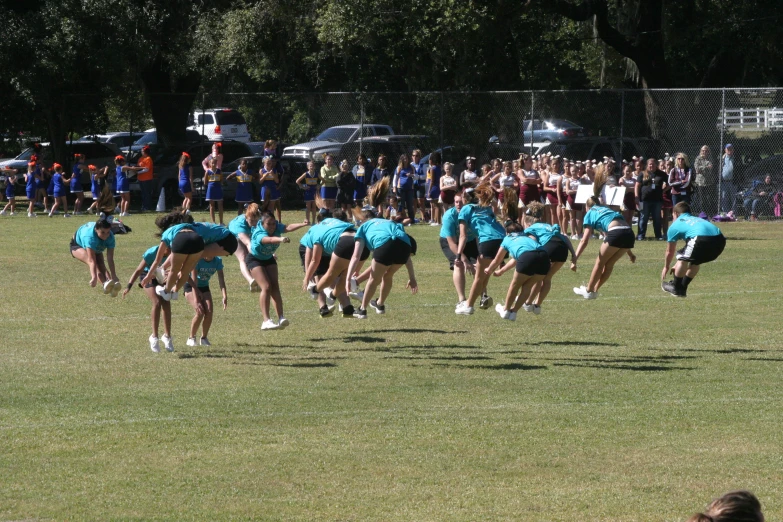 girls in blue and black cheer uniforms on green grass