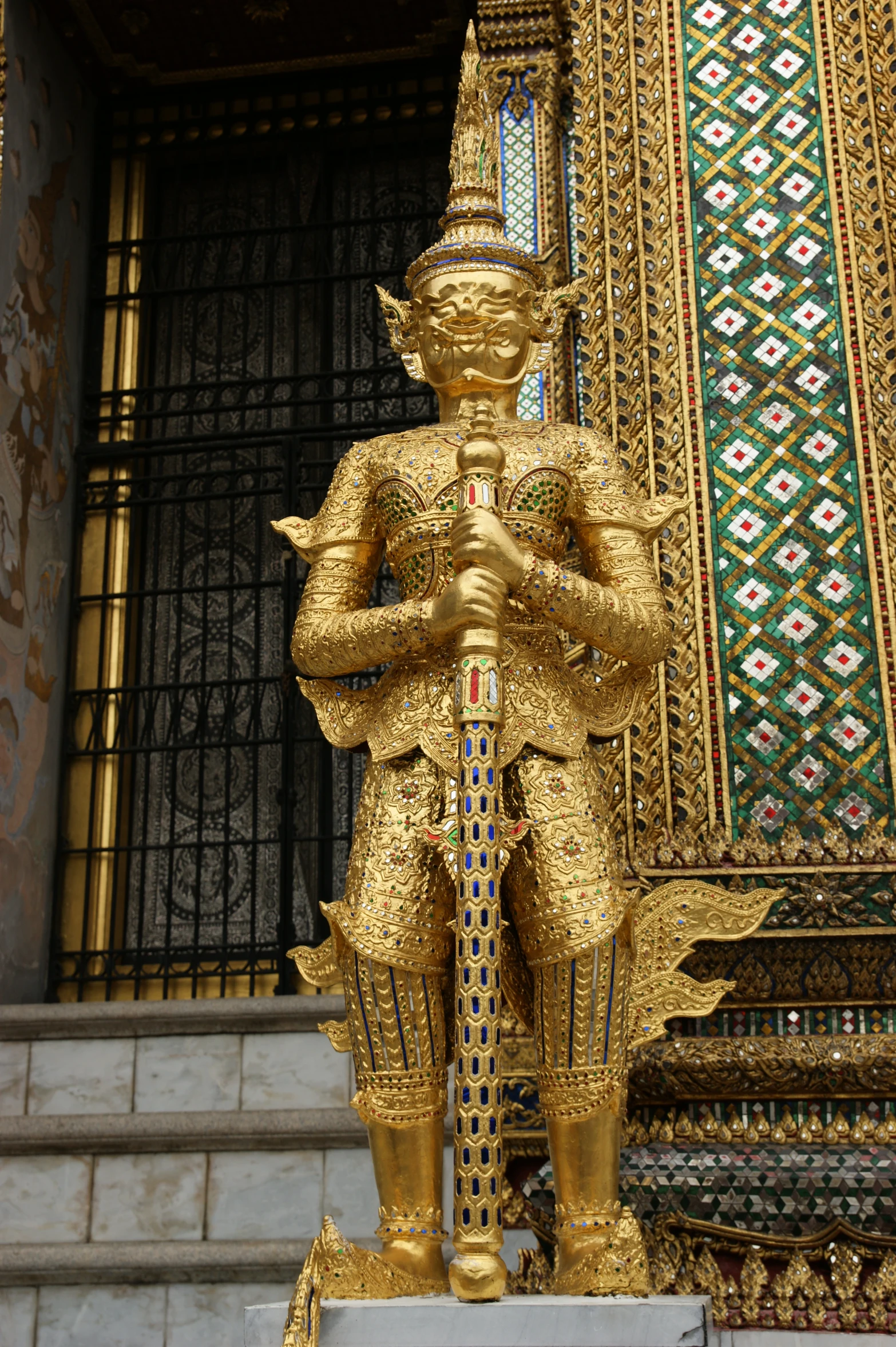 a gilded gold statue is in front of an ornate wall