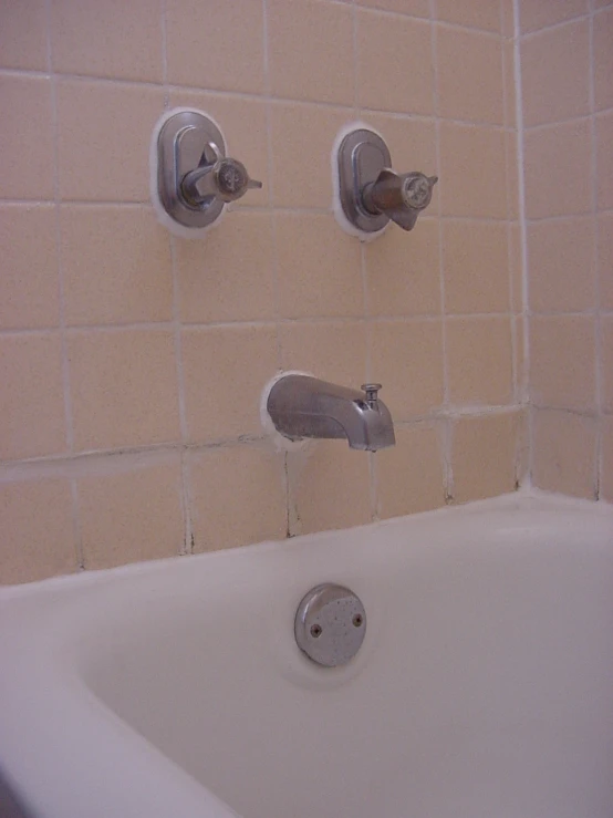 the tub faucet and two water filler are above the bathtub