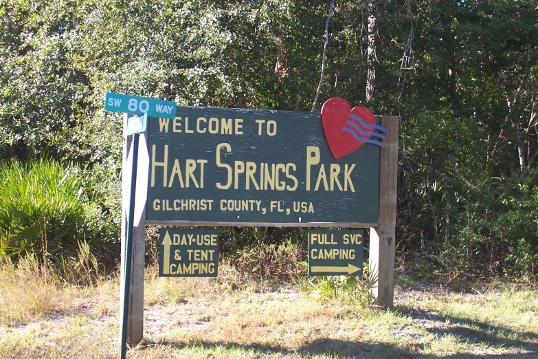 a sign for heart springs park sits near a wooded area