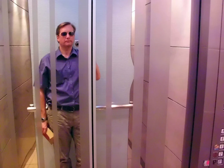 man taking picture through the reflection of himself in the elevator