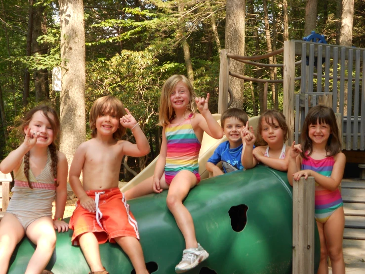 six children sitting in a green playground slide