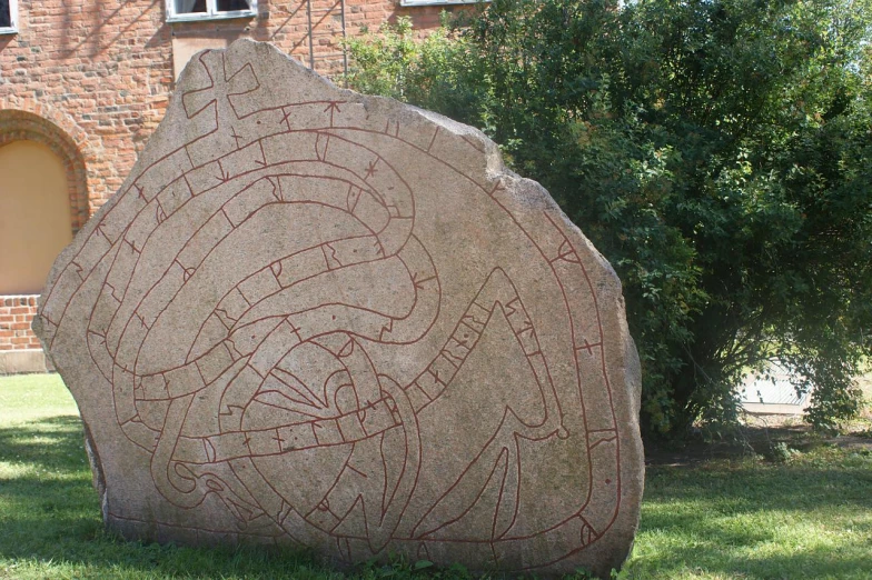 a rock with carvings on it in the grass