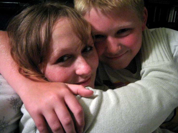 two children cuddle each other and pose for the camera