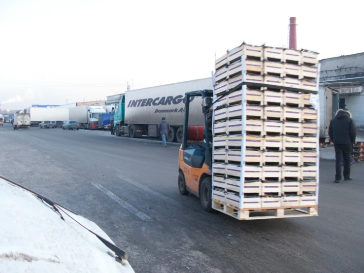 a forklift carrying a cart of containers down the road