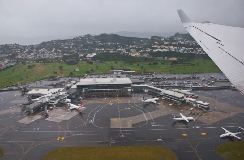 two planes sitting at their terminal while the wind moves in