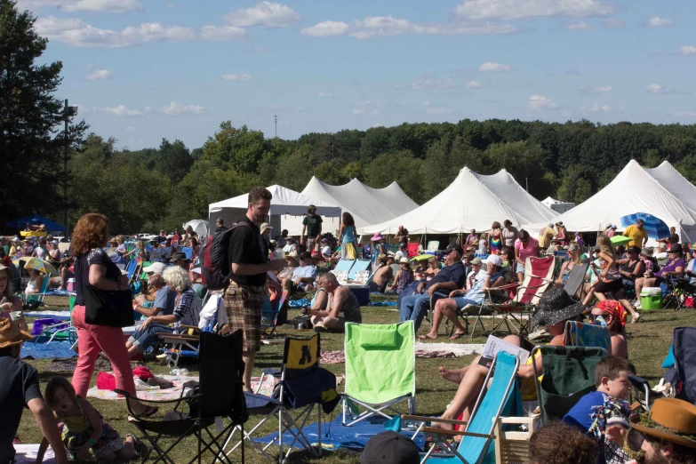 an audience of people sitting and standing in lawn chairs