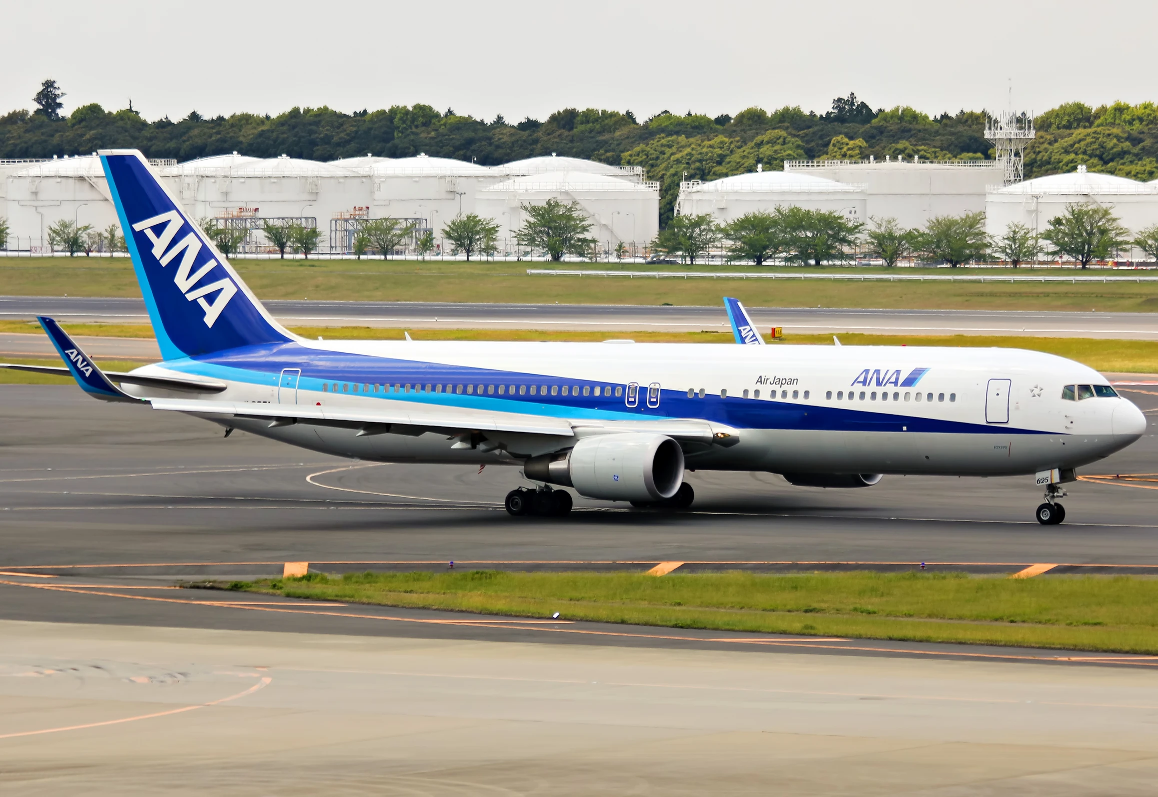 a white, blue, and black jet airliner taxiing on an airport runway