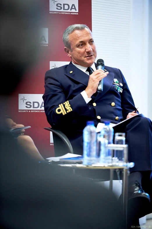 a man in a uniform talks into a microphone