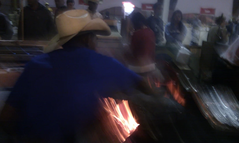 a man wearing a cowboy hat is cooking food