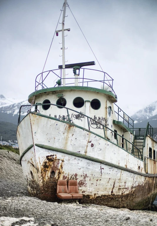 the rusty boat is docked on a rocky beach